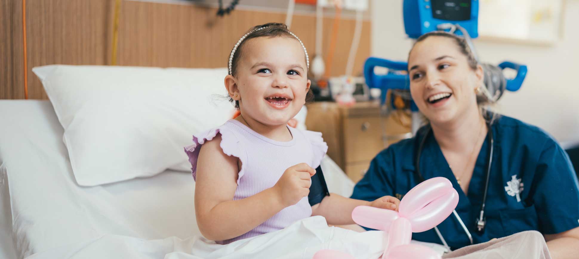 A caregiver and infant patient smile with a baloon animal