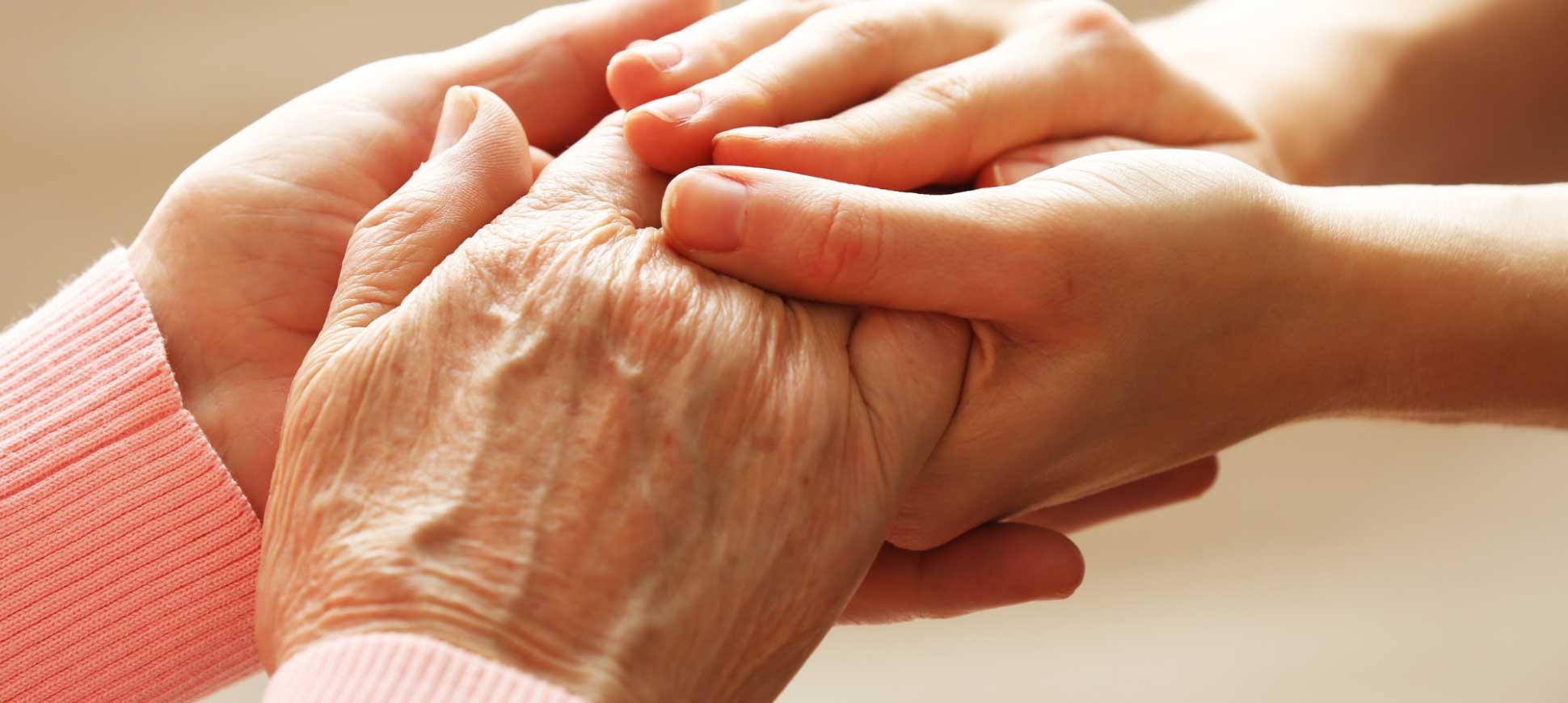 A young pair of hands hold an old pair of hands