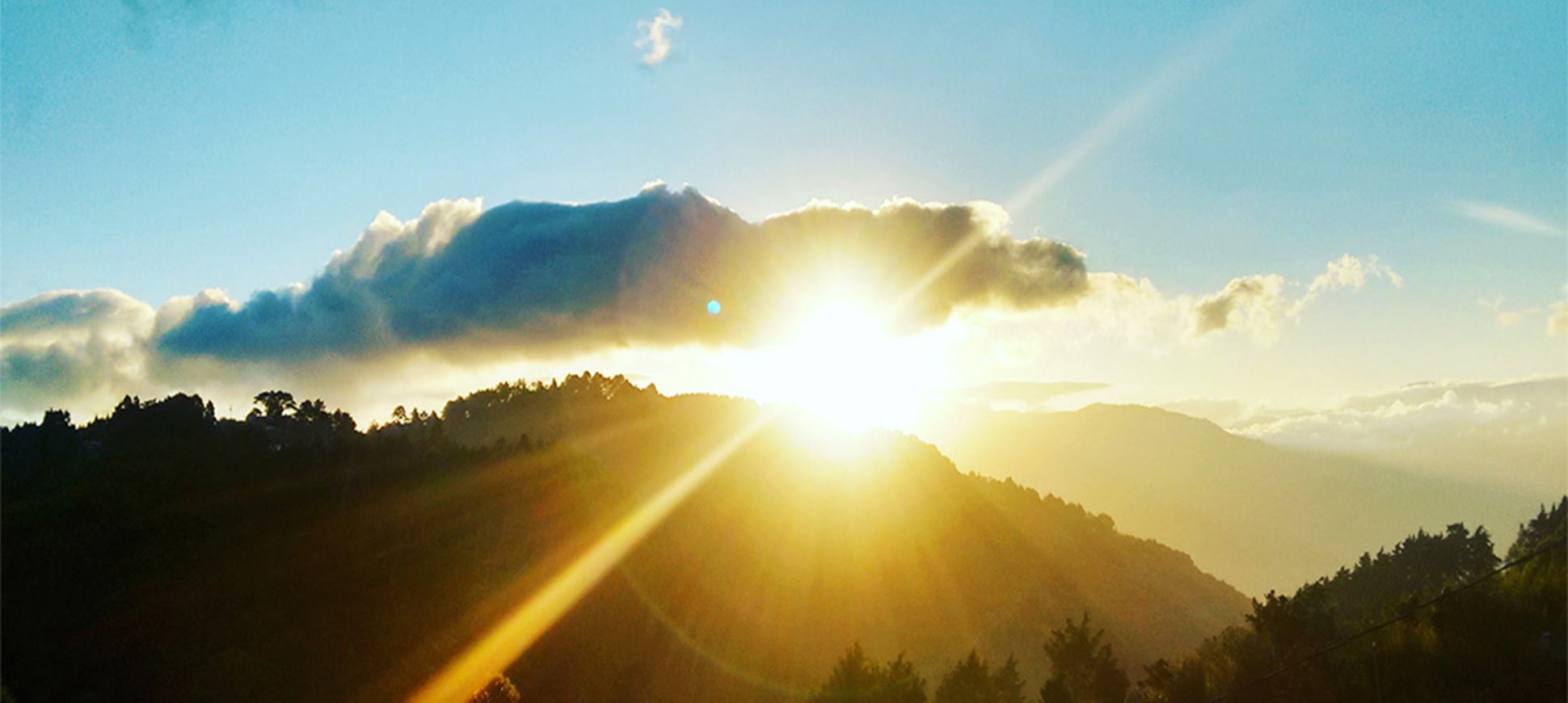 A sun peaks over the distant hill tops as it rises