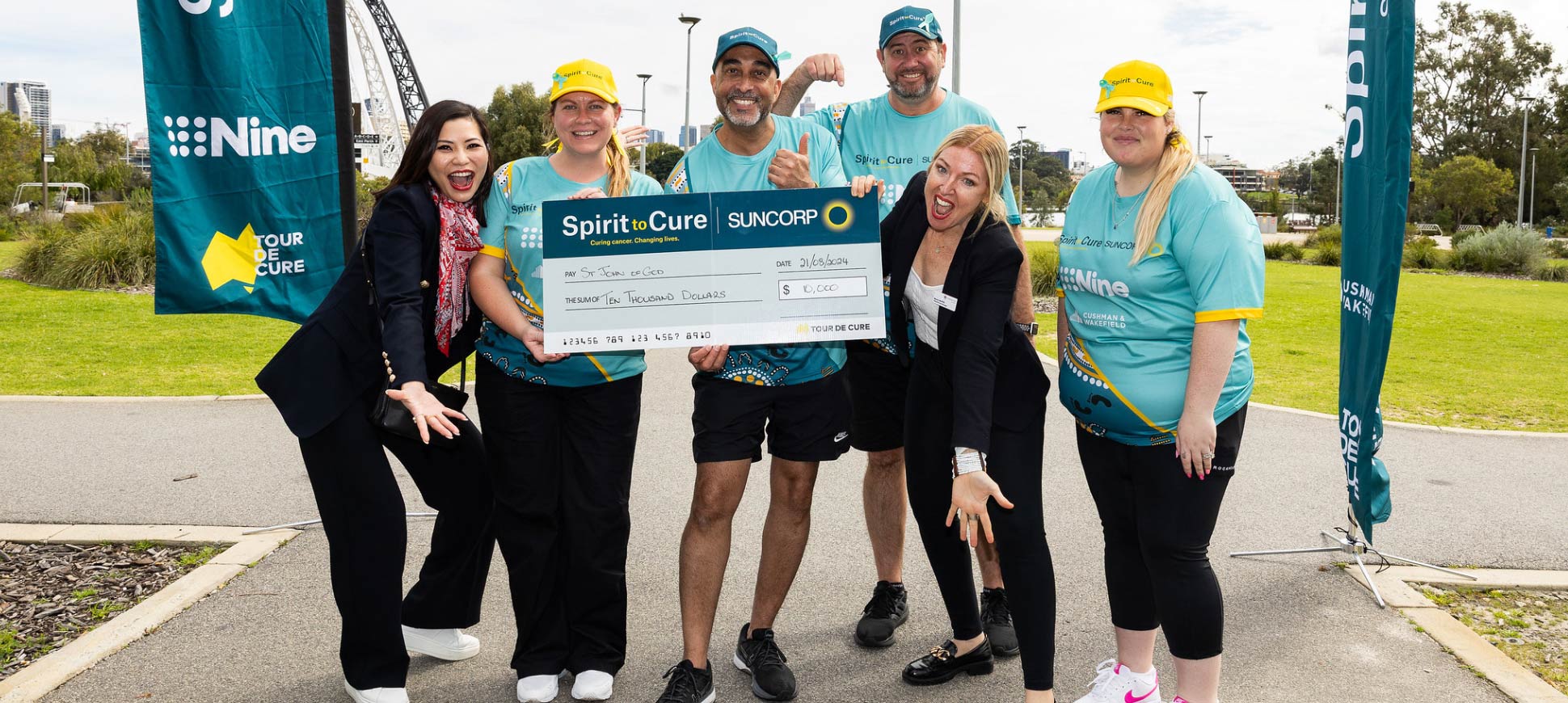 Four joggers and two Foundation team members smile as they hold a giant novelty cheque from Suncorp.