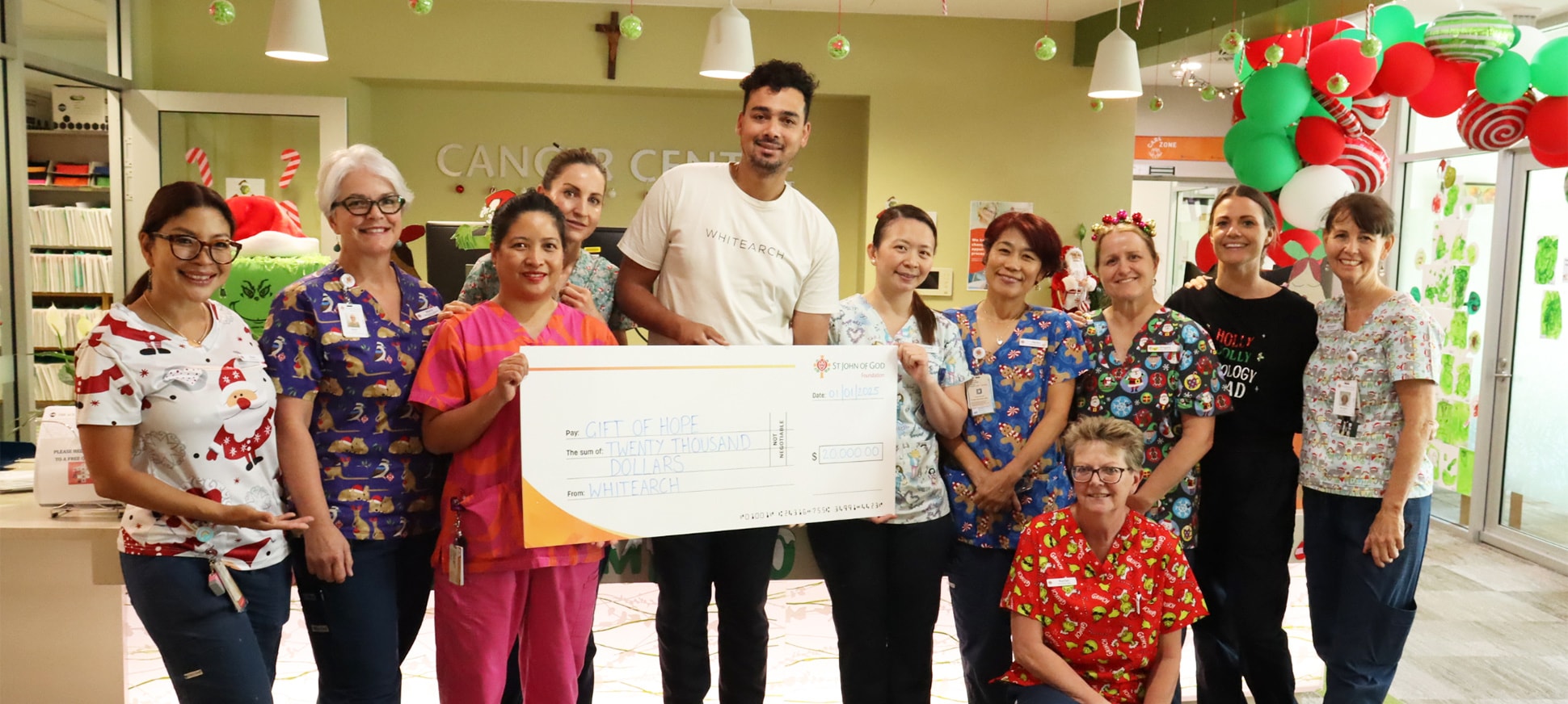 Ashby Farrell and St John of God cancer caregivers smile for a photo holding a $20,000 novelty cheque.